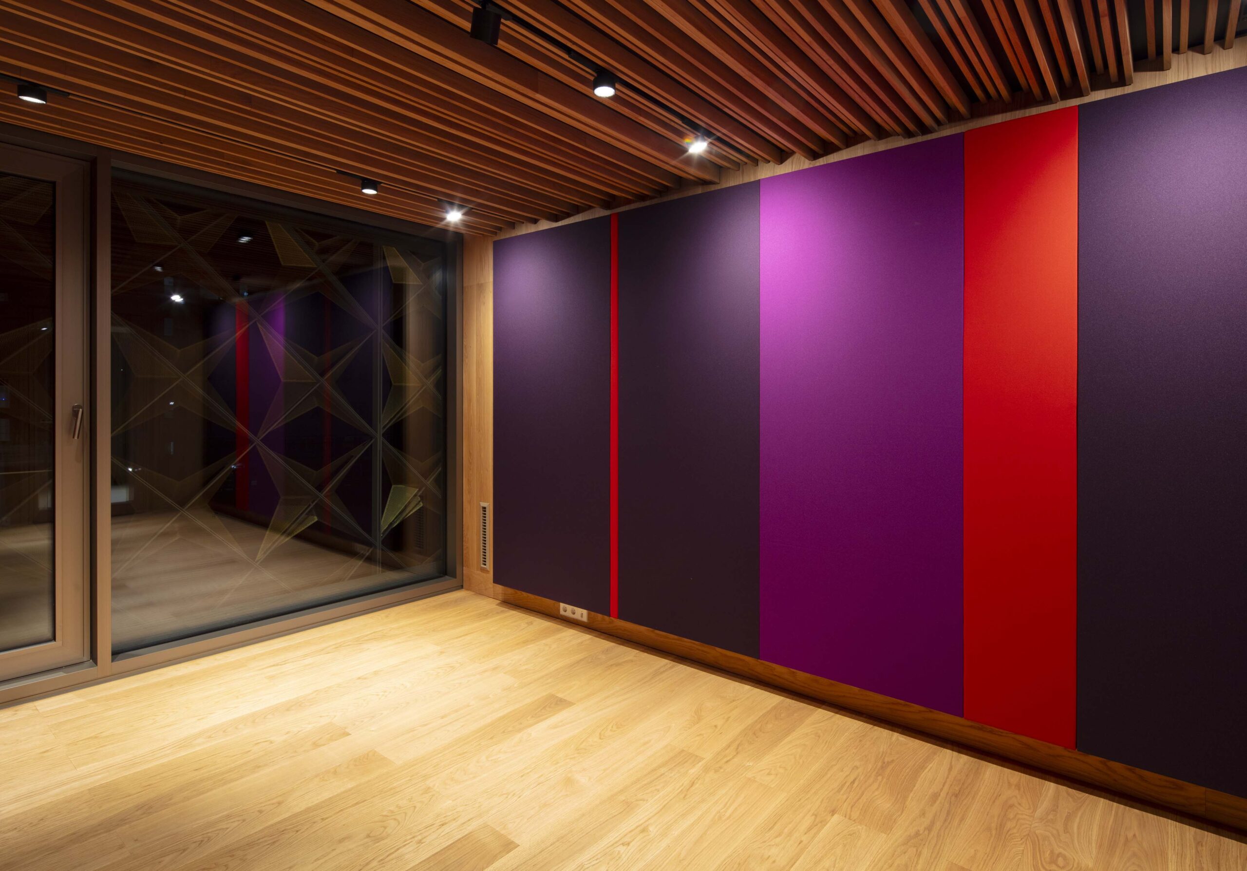 Deckenbeleuchtung bringt farbige Wand zum Strahlen. Moderne Architekturbeleuchtung mit Stromschienen und Einbauleuchten von mawa im Haus für Musik, Potsdam. Proberaumbeleuchtung, Konzertraumbeleuchtung im akustisch optimierten Proberaum des Hauses für Musik, Potsdam